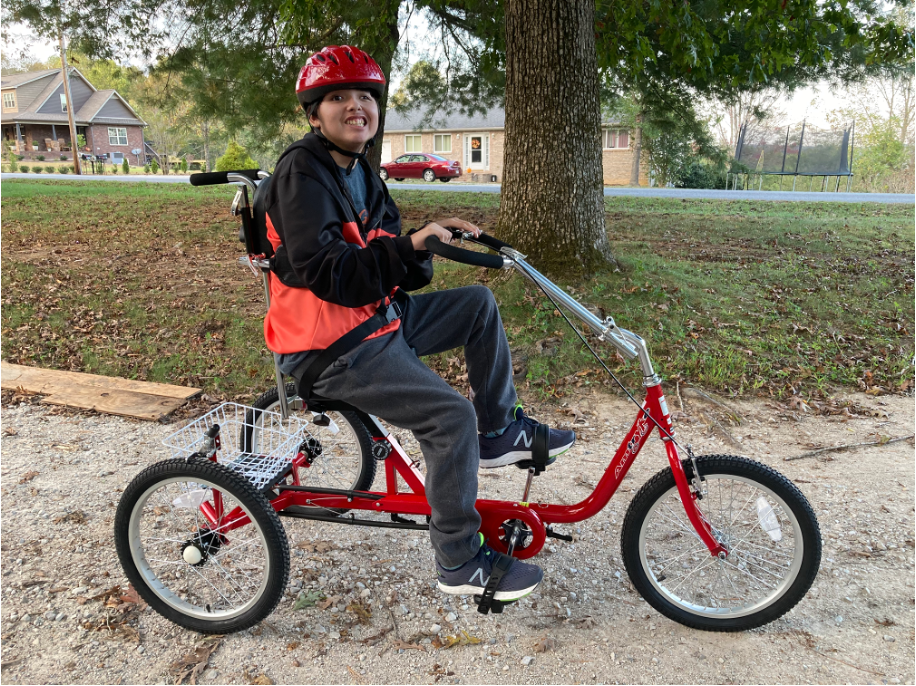 Child riding Pro Series 1420, a foot powered tricycle with additional handle bar support.